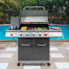 A stainless steel 4-burn Royal Gourmet gas grill with a charcoal basket, lid, side burner, and lower storage cabinet, shown outdoors by a swimming pool with palm trees in the background.