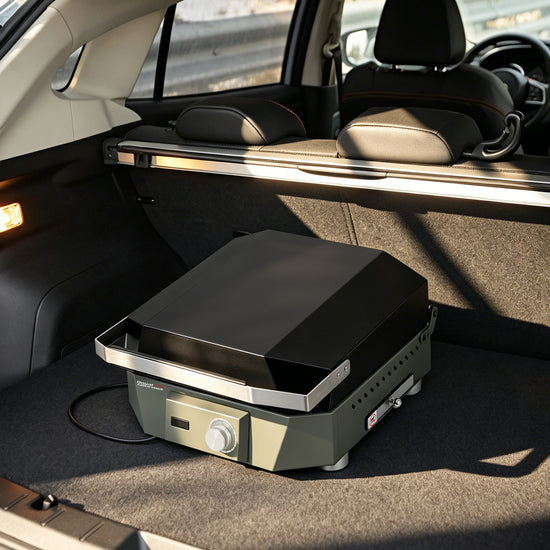 A portable electric Royal Gourmet  grill placed in the trunk of a car, with the rear seats visible in the background.