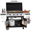 A large black and silver Royal Gourmet gas grill with the lid open, cooking food on the grates. The grill has side shelves holding condiments and vegetables, hanging utensils, a cutting board, and a propane tank in the lower compartment, all shown on a white background.