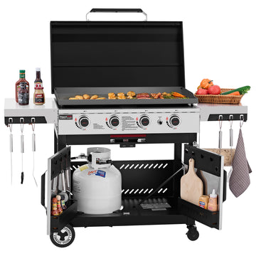 A large black and silver Royal Gourmet gas grill with the lid open, cooking food on the grates. The grill has side shelves holding condiments and vegetables, hanging utensils, a cutting board, and a propane tank in the lower compartment, all shown on a white background.