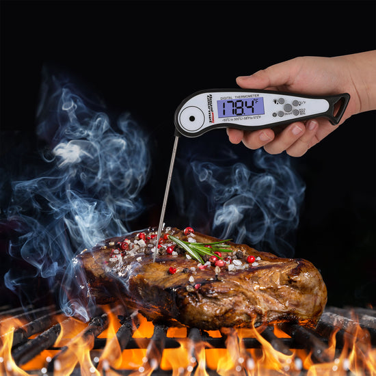 Royal Gourmet Digital thermometer reading 178.4øC on a steak with flames and smoke in the background
