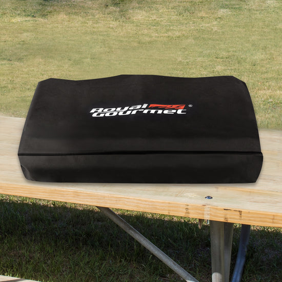 Black cover with 'Royal Gourmet' logo on a wooden table outdoors.