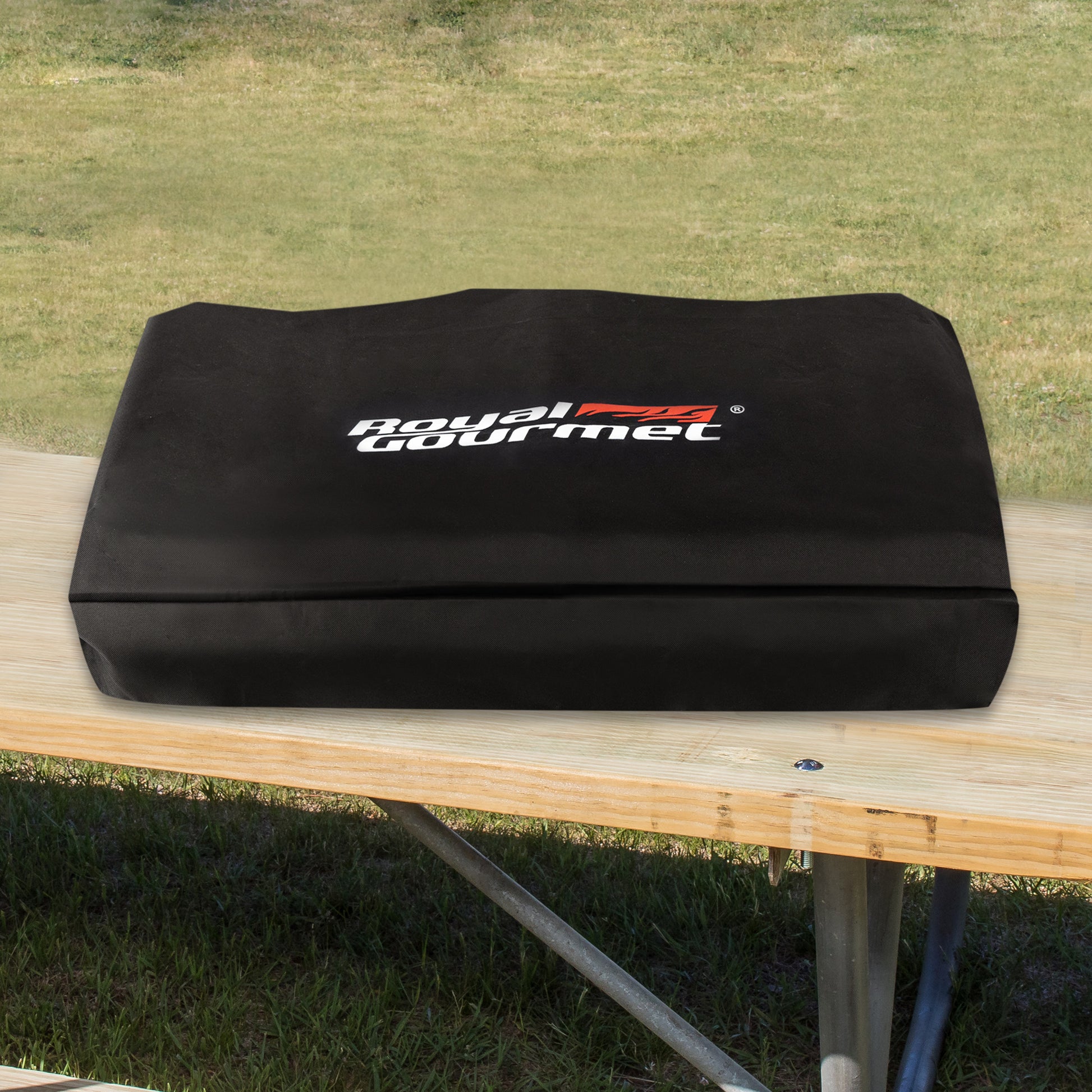 Black cover with 'Royal Gourmet' logo on a wooden table outdoors.