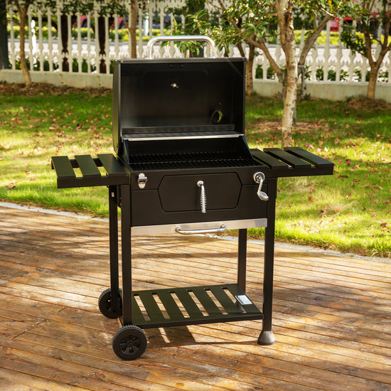 Black Royal Gourmet barbecue grill on a wooden deck with a garden background