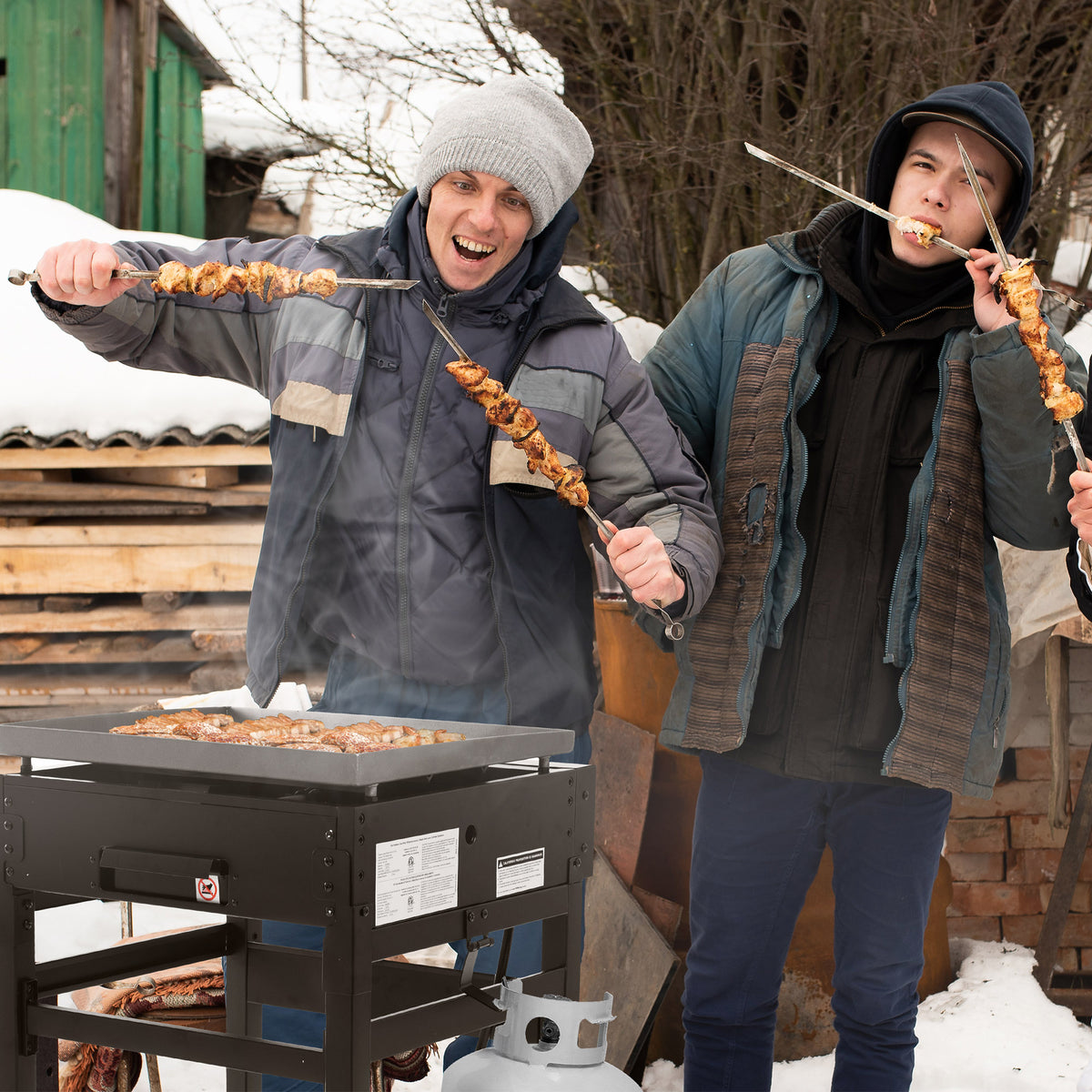 Two people grilling outdoors in a snowy setting