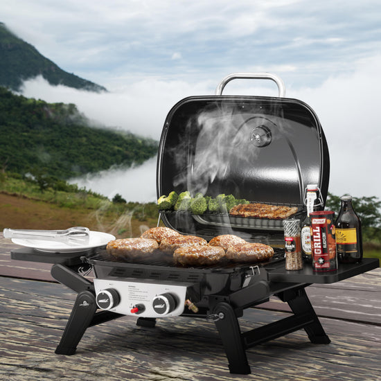 Royal Gourmet portable grill with food cooking outdoors near a scenic lake