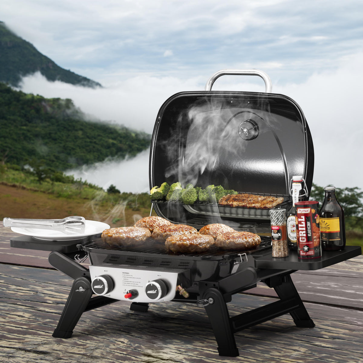 Royal Gourmet portable grill with food cooking outdoors near a scenic lake