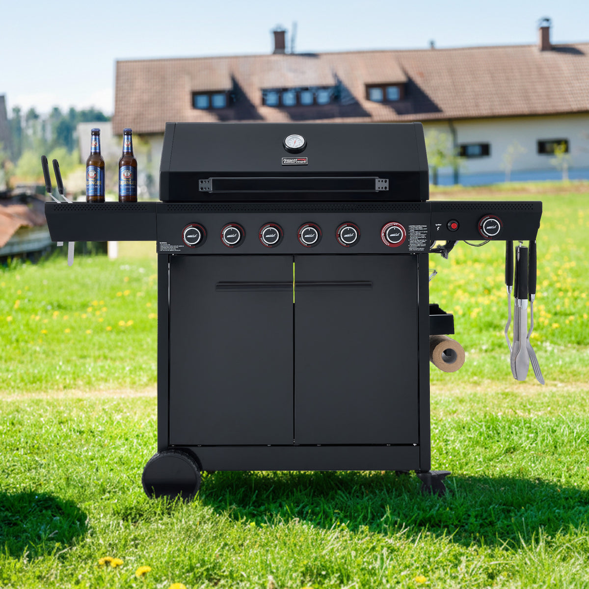 Black Royal Gourmet barbecue grill on grass with a house in the background