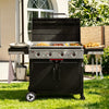 A black and stainless steel outdoor Royal Gourmet gas grill with a lid, shown on a green lawn in front of a house. The grill is open with food cooking on the flat top and side shelves, with a towel hanging from the side hook.
