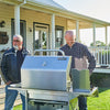 Two men standing next to a large Royal Gourmet barbecue grill on a patio