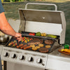 Person grilling vegetables and meats on a Royal Gourmet gas grill outdoors.