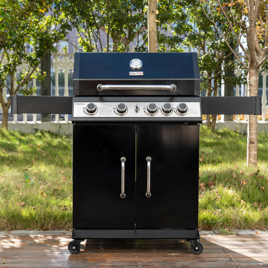 Black Royal Gourmet barbecue grill with a blue top on a wooden deck with trees in the background