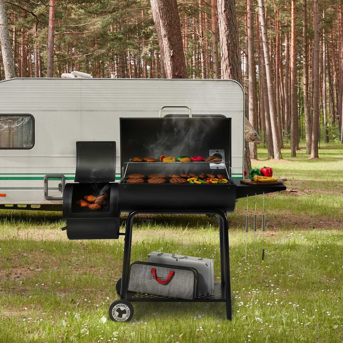 Royal Gourmet Barbecue grill with food being cooked in front of a trailer in a forest setting