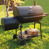 Barbecue grill on wheels with bags of charcoal in a grassy outdoor setting