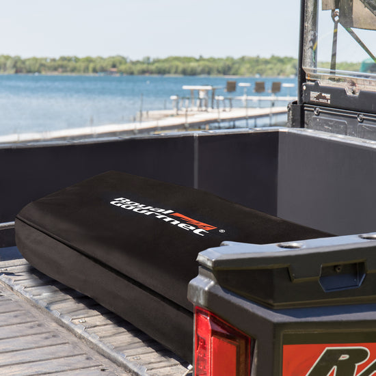 Black storage box with a brand logo on a vehicle tailgate by a lake.