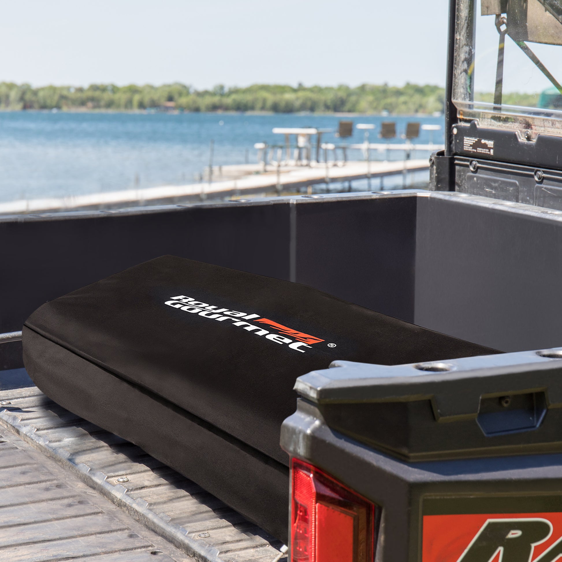 Black storage box with a brand logo on a vehicle tailgate by a lake.