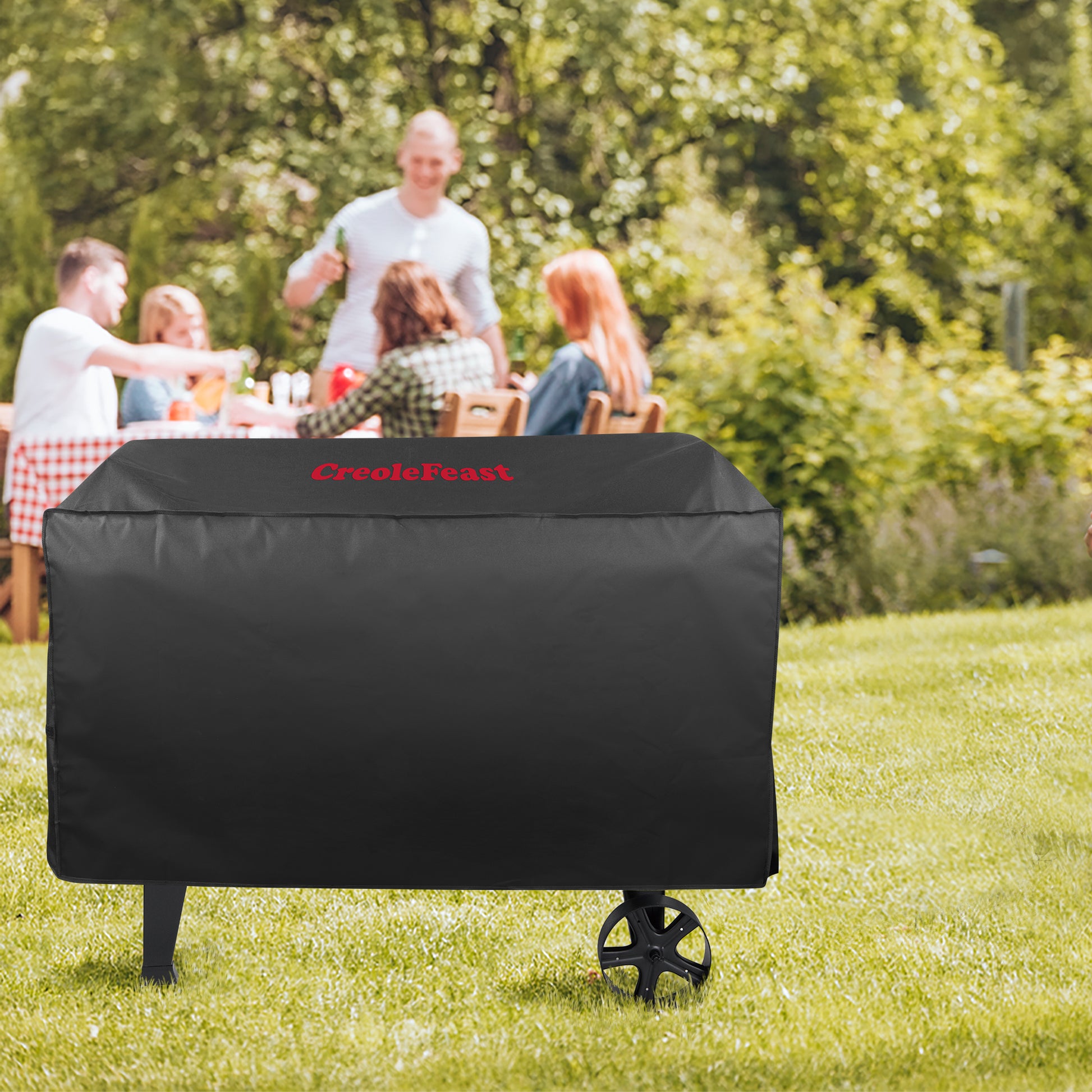 Black grill cover with 'Crescent' branding on a grassy outdoor setting with people in the background.