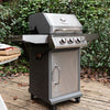 A stainless steel and dark gray Royal Gourmet gas grill with three control knobs and a side shelf, set on a wooden deck with green foliage in the background.