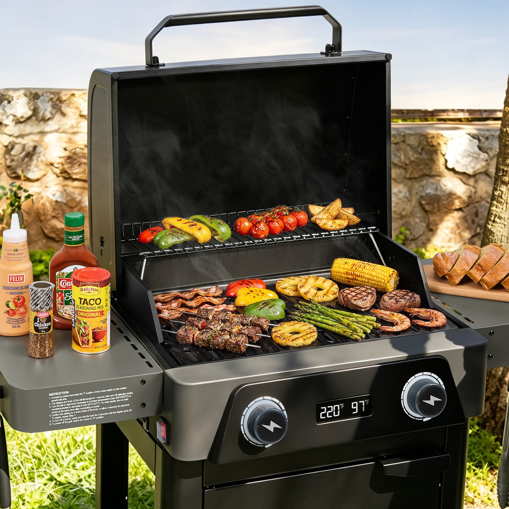 A black outdoor Royal Gourmet gas grill with a lid handle and side table, shown open and cooking various foods like burgers, steak, corn, and vegetables. Condiment bottles and sliced bread are placed on the side table, with a stone wall and grassy background.