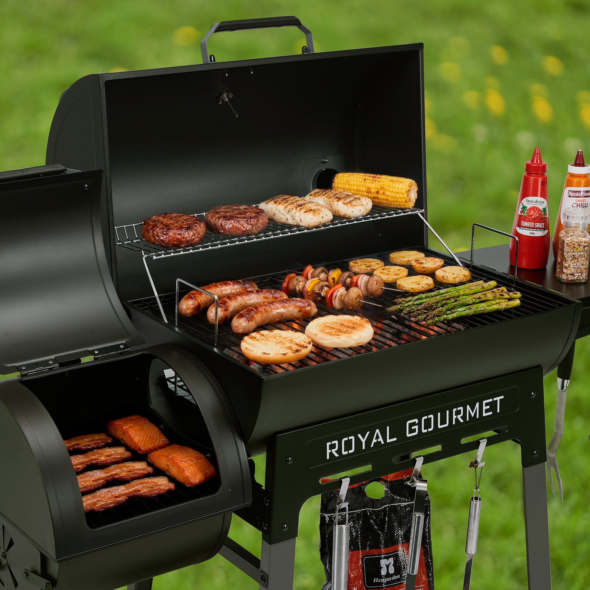 Royal Gourmet Grill with various food items on a grassy background, featuring the brand 'Royal Gourmet'.