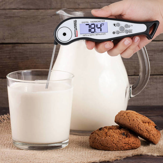 Royal Gourmet Digital thermometer measuring milk temperature with a glass of milk and cookies on a wooden surface