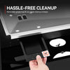 A close-up of a hand pulling open a black drawer in a stainless steel appliance, with text reading 'HASSLE-FREE CLEANUP' and a small no-smoking sticker on the drawer front.