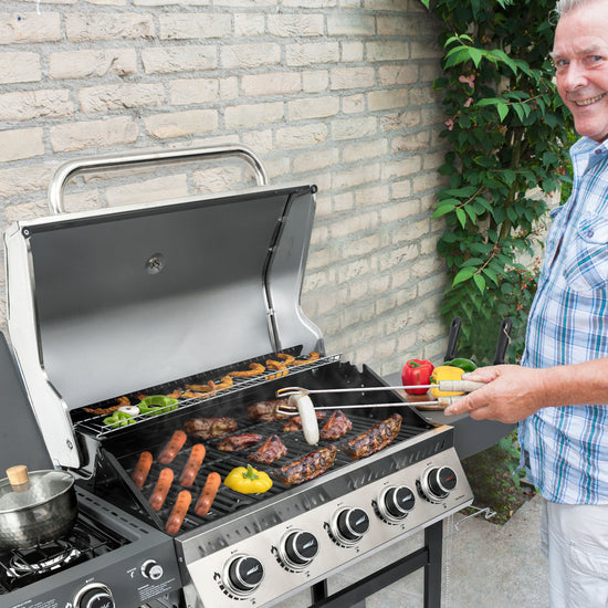 Man grilling outdoors with a Royal Gourmet barbecue and vegetables