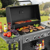 Gas grill with food and condiments on a grassy outdoor setting