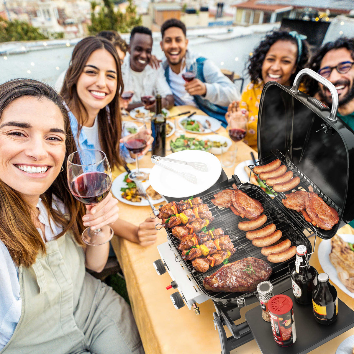 Group of people enjoying a barbecue outdoors with a Royal Gourmet portable grill.