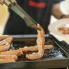 Person using tongs to handle bacon on a Royal Gourmet grill