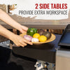 Outdoor lifestyle shot of a person placing a wooden bowl of fruits and vegetables onto a black side table of a grill. Text overlay at the top reads '2 SIDE TABLES PROVIDE EXTRA WORKSPACE'.
