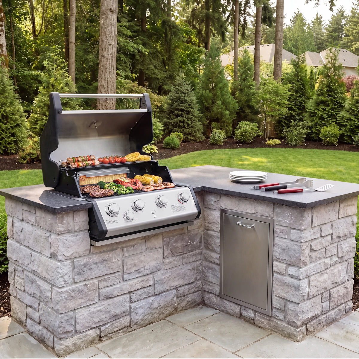 A built-in outdoor kitchen island with a gray stone brick base, dark countertop, stainless steel Royal Gourmet  grill, and side cabinet, shown in a landscaped backyard with trees and grass.
