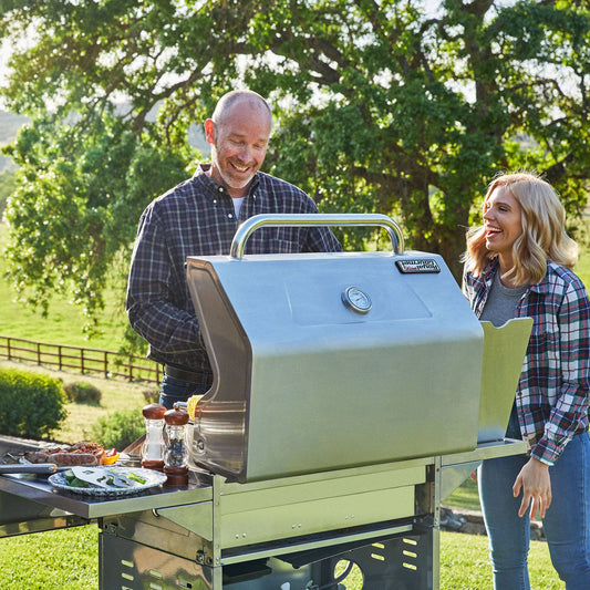 Royal Gourmet Man and woman grilling outdoors with a portable barbecue grill.