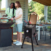 Royal Gourmet Two people standing on a wooden deck with a barbecue grill and outdoor furniture.