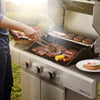 Royal Gourmet Person grilling hot dogs and sausages on a Royal Gourmet barbecue grill outdoors.