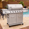 A stainless steel Royal Gourmet outdoor gas grill with side tables and dual storage cabinets, shown on a tiled patio next to a swimming pool.