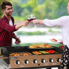 Two people grilling outdoors with a Royal Gourmet portable grill and enjoying wine.