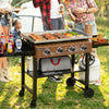 Portable Royal Gourmet grill on a grassy outdoor setting with people around