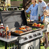 A stainless steel outdoor Royal Gourmet gas grill with the lid open, cooking burgers, steak, eggs, peppers, and asparagus on a griddle tray. Condiment bottles sit on the side table, and a family is standing and sitting nearby in a backyard setting.