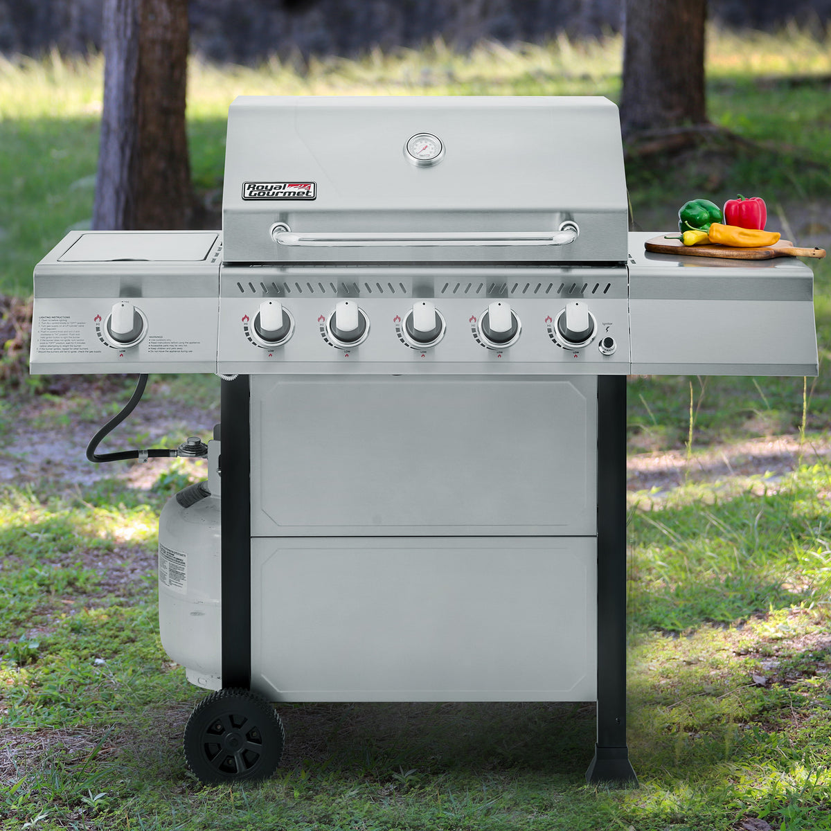 Royal Gourmet Stainless steel grill on wheels in an outdoor setting with trees and grass.