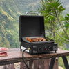 Royal Gourmet Portable grill with food on a wooden table outdoors with a mountainous background