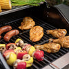 Grilled chicken pieces, sausages, mushrooms, bell peppers, and corn on a black outdoor Royal Gourmet grill with asparagus visible at the top.