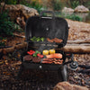 Portable Royal Gourmet grill with food cooking outdoors near a natural setting