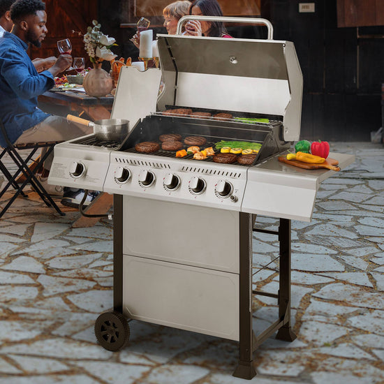 Gas grill on a patio with people dining in the background