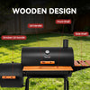 A black Royal Gourmet outdoor smoker grill with wooden shelves and handles, shown on grass with labeled callouts reading 'Wooden Design' and pointing to the smoker lid handle, front shelf, and side shelf.