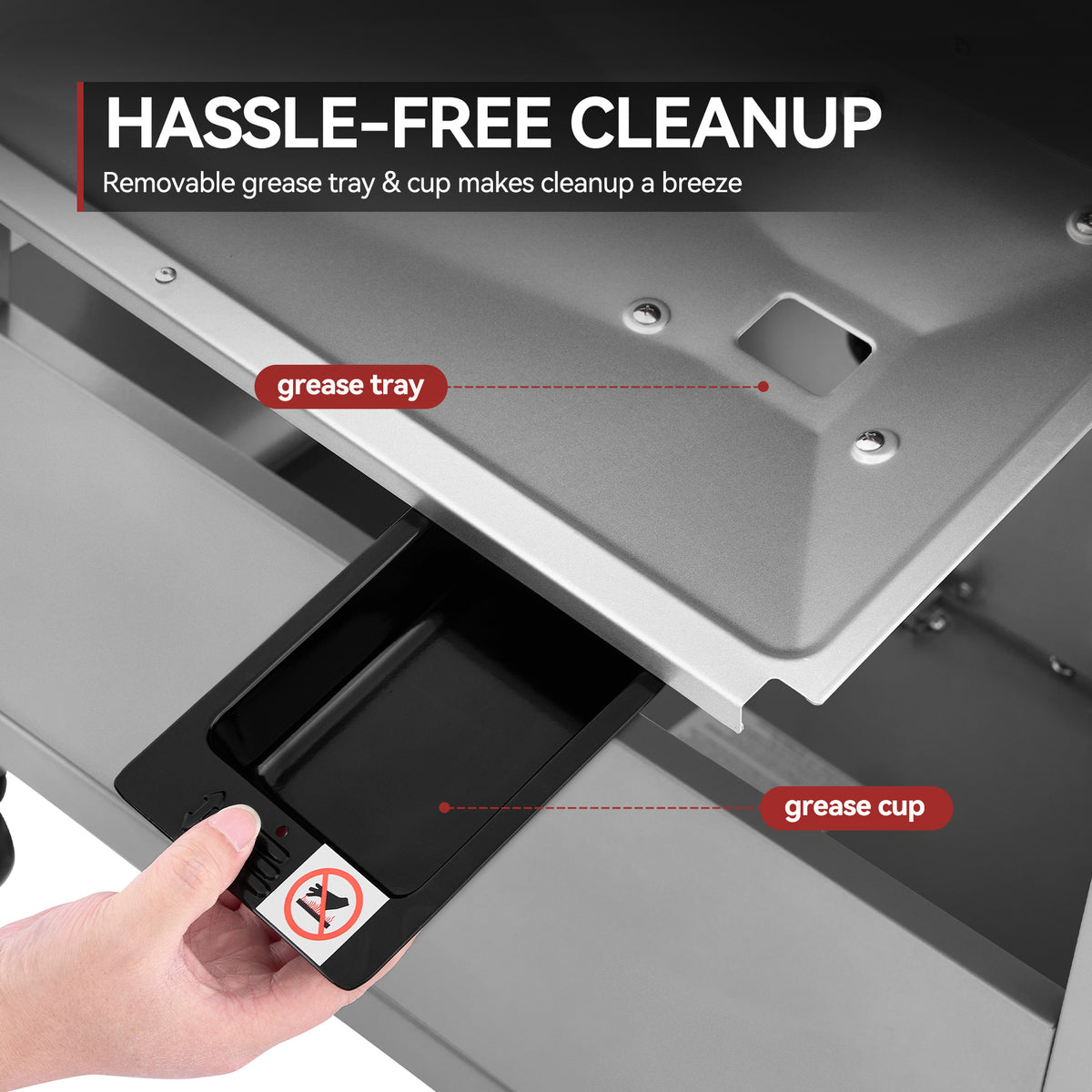 Close-up of a metal appliance drawer being pulled open to reveal a black removable grease tray and cup, with overlaid labels reading 'grease tray' and 'grease cup' and a headline 'HASSLE-FREE CLEANUP'. A hand is visible holding the drawer.