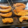 Sliced peaches being grilled on a hot surface with skewers.