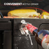 Bottle opener attached to a Royal Gourmet grill with a bottle being opened, surrounded by food.