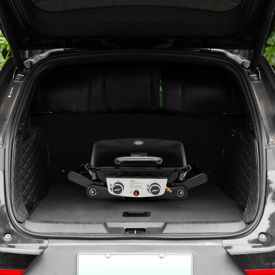 A compact black Royal Gourmet gas grill with a silver control panel is folded and displayed inside the open trunk of a black vehicle.