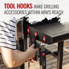 A person's hand hangs a tool from a black grill's side-mounted hook, with other tools stored on the hook. Large text at the top reads 'TOOL HOOKS MAKE GRILLING ACCESSORIES WITHIN ARM'S REACH'.